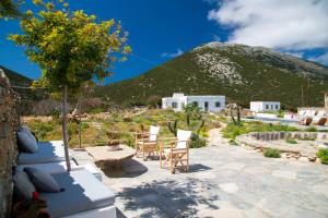 a patio with chairs and a table and a mountain at Sifnos Themonies in Apollonia