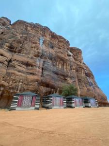 two beds on a beach next to a rock wall at Shahrazad desert, Wadi Rum in Wadi Rum