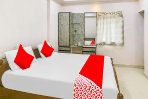 een slaapkamer met een groot wit bed met rode kussens bij OYO Flagship 81201 Sls Luxury Suites in Visakhapatnam