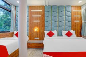 a bedroom with two beds with red pillows at OYO Flagship Hotel Reet Villa in Ahmedabad