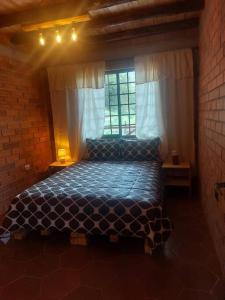 een slaapkamer met een bed in een kamer met een raam bij Casa del Rio in the Andes in Gualaceo