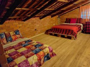 een slaapkamer met 2 bedden en een bakstenen muur bij Casa del Rio in the Andes in Gualaceo