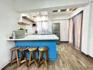 a kitchen with a blue island with four stools at Casa Colibri in Roatan