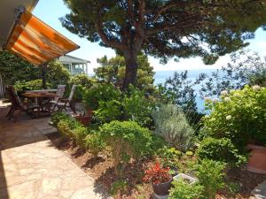 ogród ze stołem, krzesłami i roślinami w obiekcie Villa Maristika w Omišu