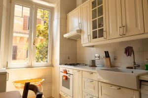 a kitchen with white cabinets and a sink and a window at Borghese Magnolia Suite in Rome