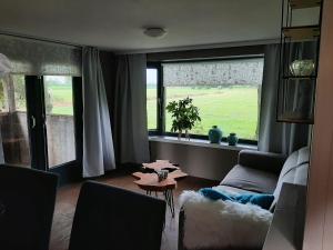 een woonkamer met een bank, een tafel en een raam bij Pak oe rust, bij stacaravan Busscher in Geesteren