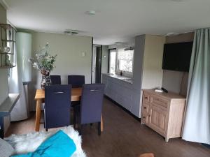 a dining room with a table and chairs and a television at Pak oe rust, bij stacaravan Busscher in Geesteren