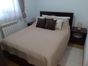 Cama con sábanas y almohadas blancas y negras en Apartman VIAGGIO en Sremska Mitrovica