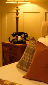 un teléfono sentado en una mesa junto a una cama en Simonstone Hall Hotel en Hawes