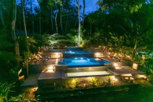 a swimming pool with lights in a garden at night at Copa De Arbol Beach & Rainforest Resort in Drake
