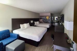 una habitación de hotel con 2 camas y una silla azul en Clarion Pointe Statesville, en Statesville