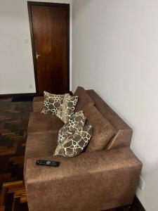 a couch with two pillows and a remote control on it at Ap Central c/ Garagem in Ponta Grossa