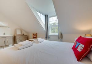 een slaapkamer met een groot wit bed met een rood kussen bij Glenisla in Sidmouth