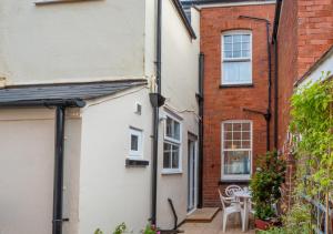 un callejón entre dos edificios con mesa y sillas en Glenisla en Sidmouth