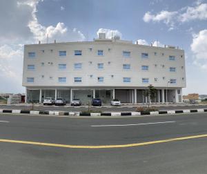 a large white building with cars parked in a parking lot at اجنحة ريام in Al Namas