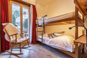 a bedroom with bunk beds and a chair and a window at Nev 404 Centrally located 6 pax apartment and garage in La Tzoumaz
