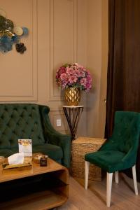 - un salon avec un canapé vert et un vase de fleurs dans l'établissement Royal Max hotel & spa, à Almaty