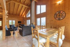 a dining room with a table and a clock on the wall at La Taniere - Cozy chalet with incredible views and parking in La Tzoumaz