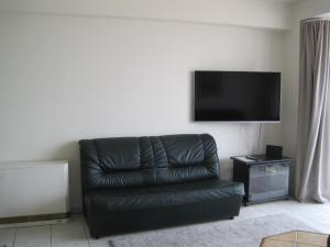 a black leather couch in a living room with a flat screen tv at Beachview Pier Blankenberge in Blankenberge