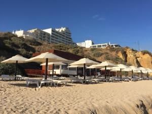 uma praia com mesas e guarda-sóis na areia em T1 - Praia da Rocha - com Vistas de Mar e Terraço em Portimão