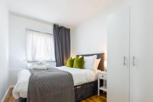 Un dormitorio con una cama con almohadas verdes y una ventana en Beautiful House, en Londres