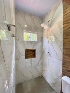 a bathroom with a marble shower with a window at Chalé canto da mata in Pirenópolis +21 photos
