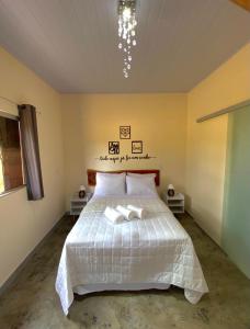 a bedroom with a white bed with two towels on it at Chalé canto da mata in Pirenópolis