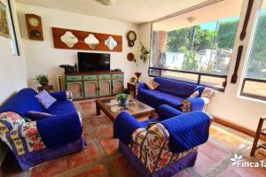 uma sala de estar com sofás azuis e uma televisão em Finca Taino. Hermosa casa con alberca em Jiutepec