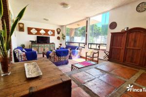 Finca Taino. Hermosa casa con alberca في جيوتيبيك: غرفة معيشة مع طاولة خشبية وكراسي زرقاء