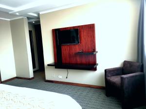 a room with a bed and a tv and a chair at Edificio Akros in Quito