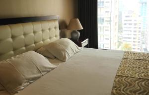 a bedroom with a large white bed with a large window at Edificio Akros in Quito