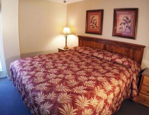 a bedroom with a large bed with a red comforter at Island Gulf Resort, a VRI resort in St Pete Beach
