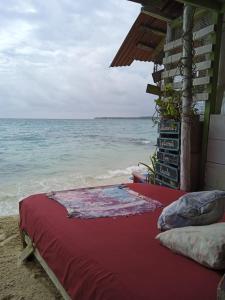 uma cama sentada na praia junto ao oceano em DespertArte espacio de Arte y Hospedaje em Playa Blanca