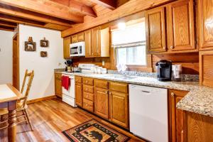 a kitchen with wooden cabinets and white appliances at Orleans Retreat with Private Hot Tub and Fireplace! 
