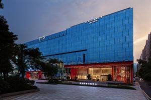 a tall glass building with a sign on it at Courtyard by Marriott Shenzhen Northwest in Bao'an