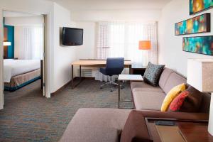 a hotel room with a couch and a desk and a bed at Residence Inn Portland Scarborough in Scarborough