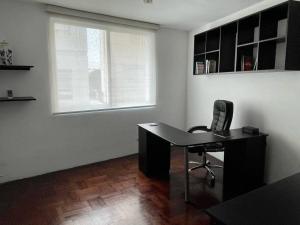 a desk and a chair in a room with a window at Vintage Apt in the Heart of Ovalo Gutierrez in Lima