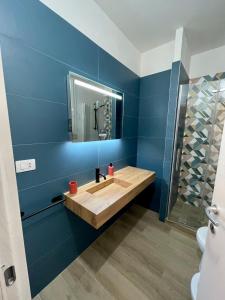 La salle de bains est pourvue d'un lavabo en bois et d'un miroir. dans l'établissement Palazzo Lussuoso 4 stanze 4 bagni, à Racale