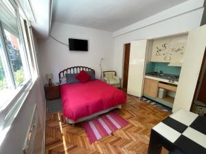 1 dormitorio con cama roja y escritorio en Imperdible Monoambiente en Palermo Chico 10min Aeroparque 100m Mater Dei en Buenos Aires