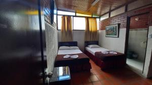 a small room with two beds and a window at HOTEL DEL PARQUE in Calarcá