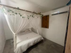 a small bedroom with a bed with a canopy at Le Paradis créole in Terre-de-Haut