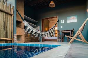 a swimming pool with a hammock in a house at Magaral Corais Chalé in Pôrto de Pedras