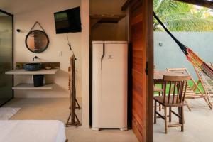 a room with a refrigerator and a table and a table at Magaral Corais Chalé in Pôrto de Pedras