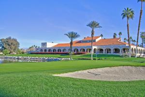 a golf course with a building and palm trees at PY732 - Champion Haven - Meredith Lodging in Palm Desert