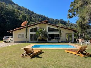 una casa con piscina y 2 sillas de césped en Sitio Haras Vitoria, en Teresópolis