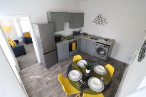 a kitchen and dining room with a table and yellow chairs at Modern 3 Double Bedroom Town Centre Maisonette in Morecambe