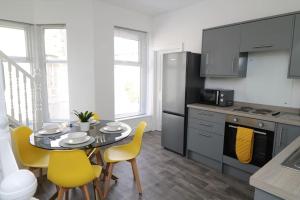 a kitchen with a table and yellow chairs in a kitchen at Modern 3 Double Bedroom Town Centre Maisonette in Morecambe
