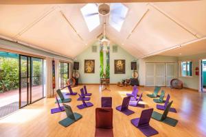 Huelo的住宿－Gardenia Room on Tropical Lush Farm in Haiku, Maui，铺有木地板的大型客房配有紫色椅子