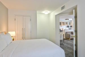 a white bedroom with a bed and a kitchen at TownePlace Suites Tallahassee North/Capital Circle in Tallahassee