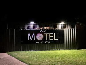 Deniliquin Motel في دينيليكين: علامة على جانب السياج في الليل